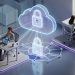 Illustration isométrique bleue et violette d’une entreprise hybride reliant des collaborateurs au bureau et en télétravail באמצעות un cloud, des ordinateurs, des smartphones et un cadenas symbolisant la gestion centralisée des identités.